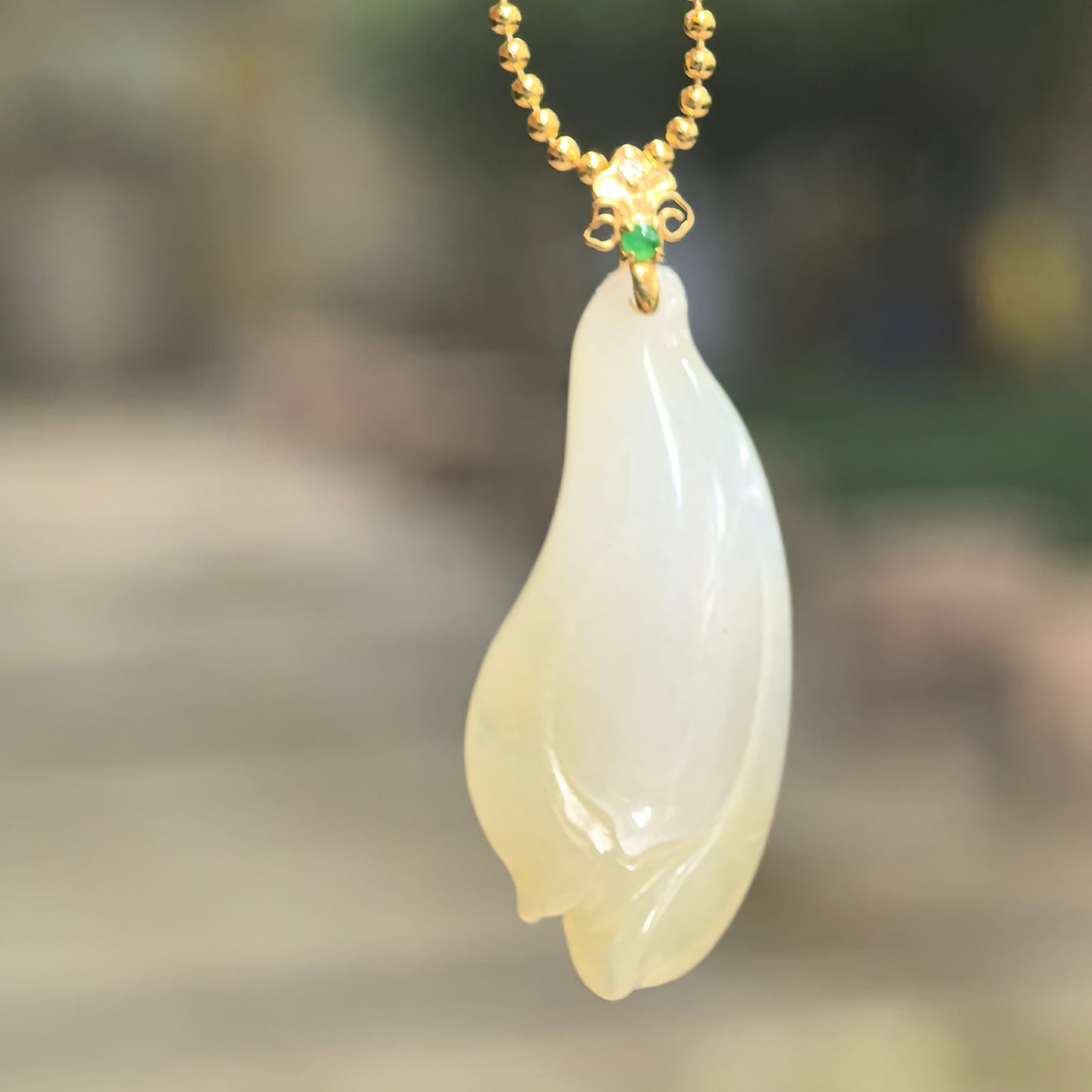 Natural Grade-A icy glutinous pale yellow magnolia jadeite pendant hanging from a chain with an 18K gold bail.
