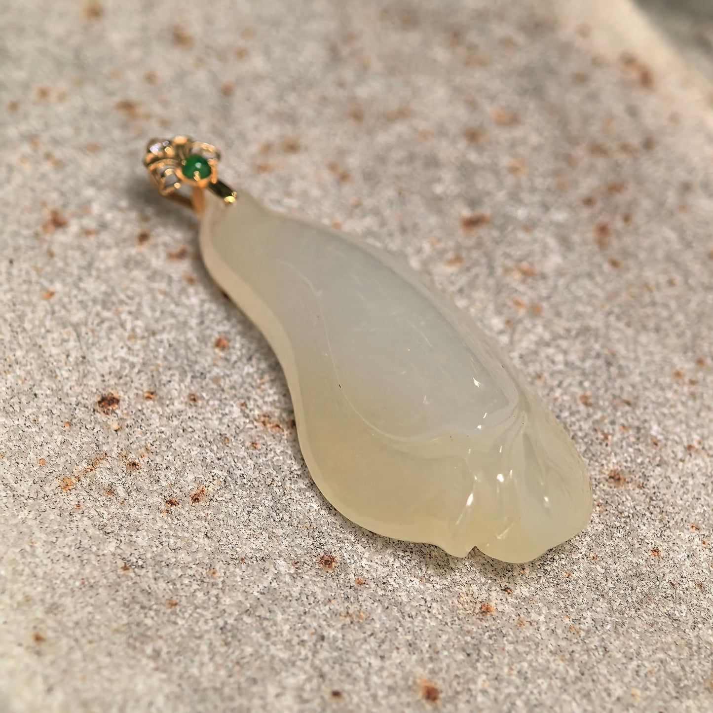 Close-up of icy glutinous pale yellow magnolia jadeite pendant showing smooth carved petals, natural translucency, and polished surface.