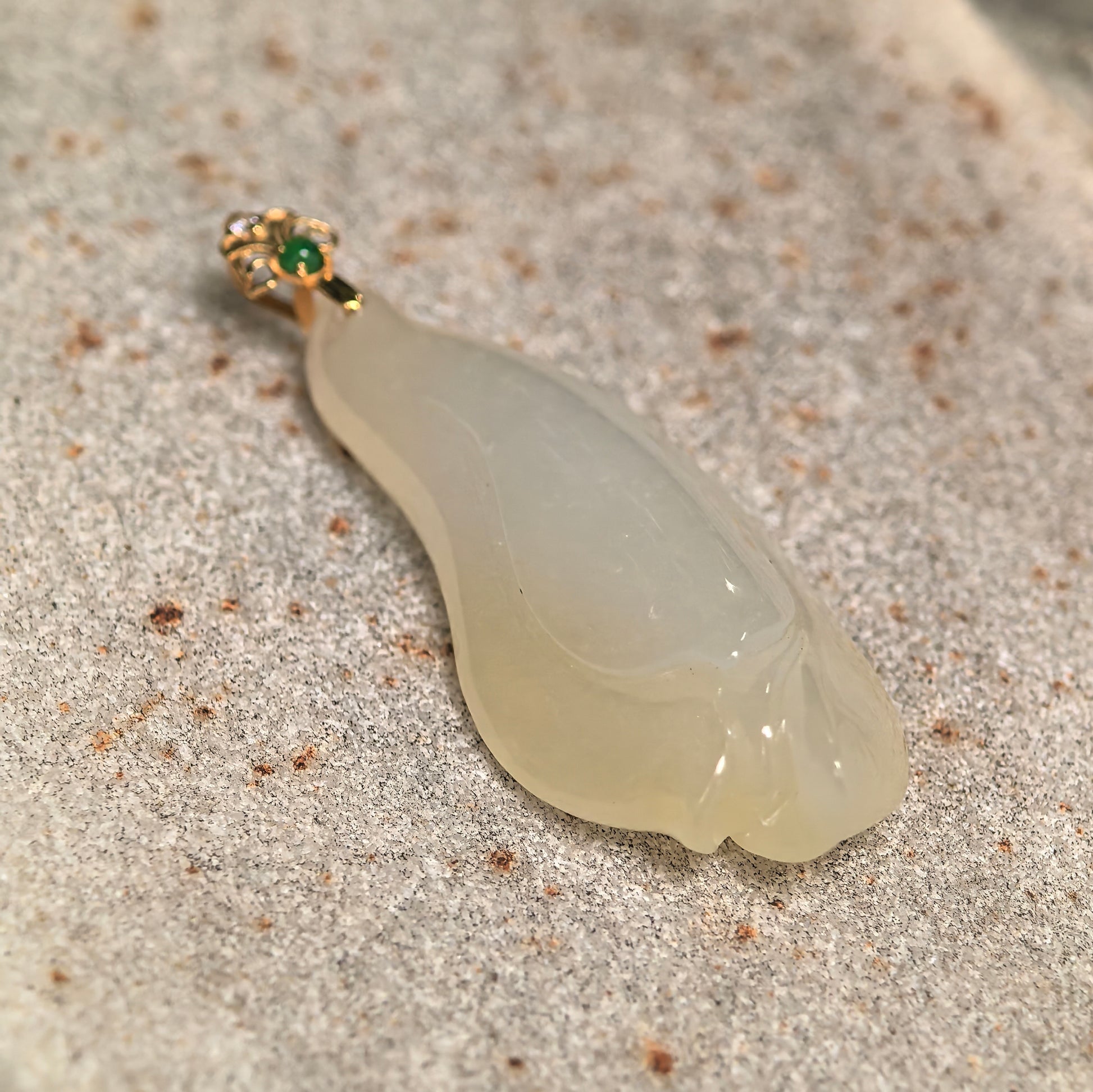 Close-up of icy glutinous pale yellow magnolia jadeite pendant showing smooth carved petals, natural translucency, and polished surface.