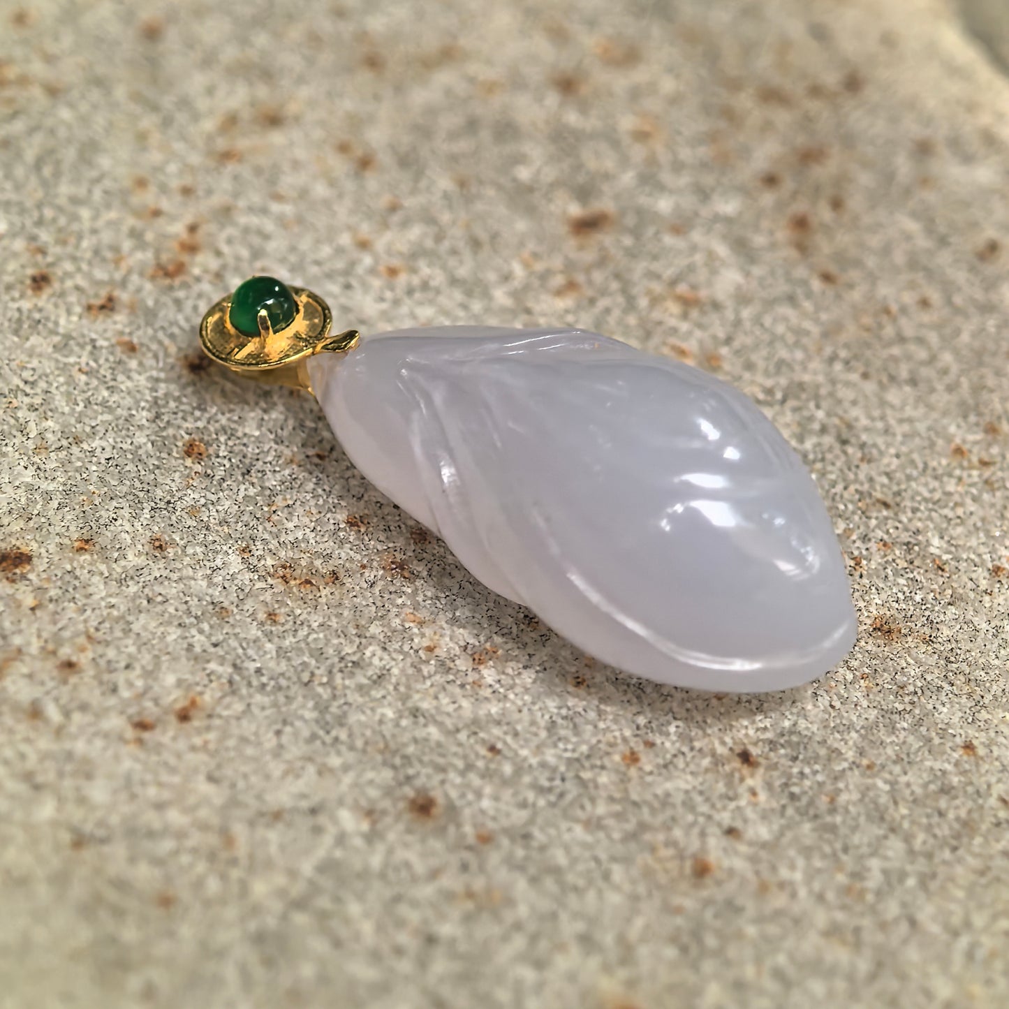 Close-up of lavender magnolia jadeite pendant showing layered floral carving, polished surface, and green accent on the 18K gold bail.