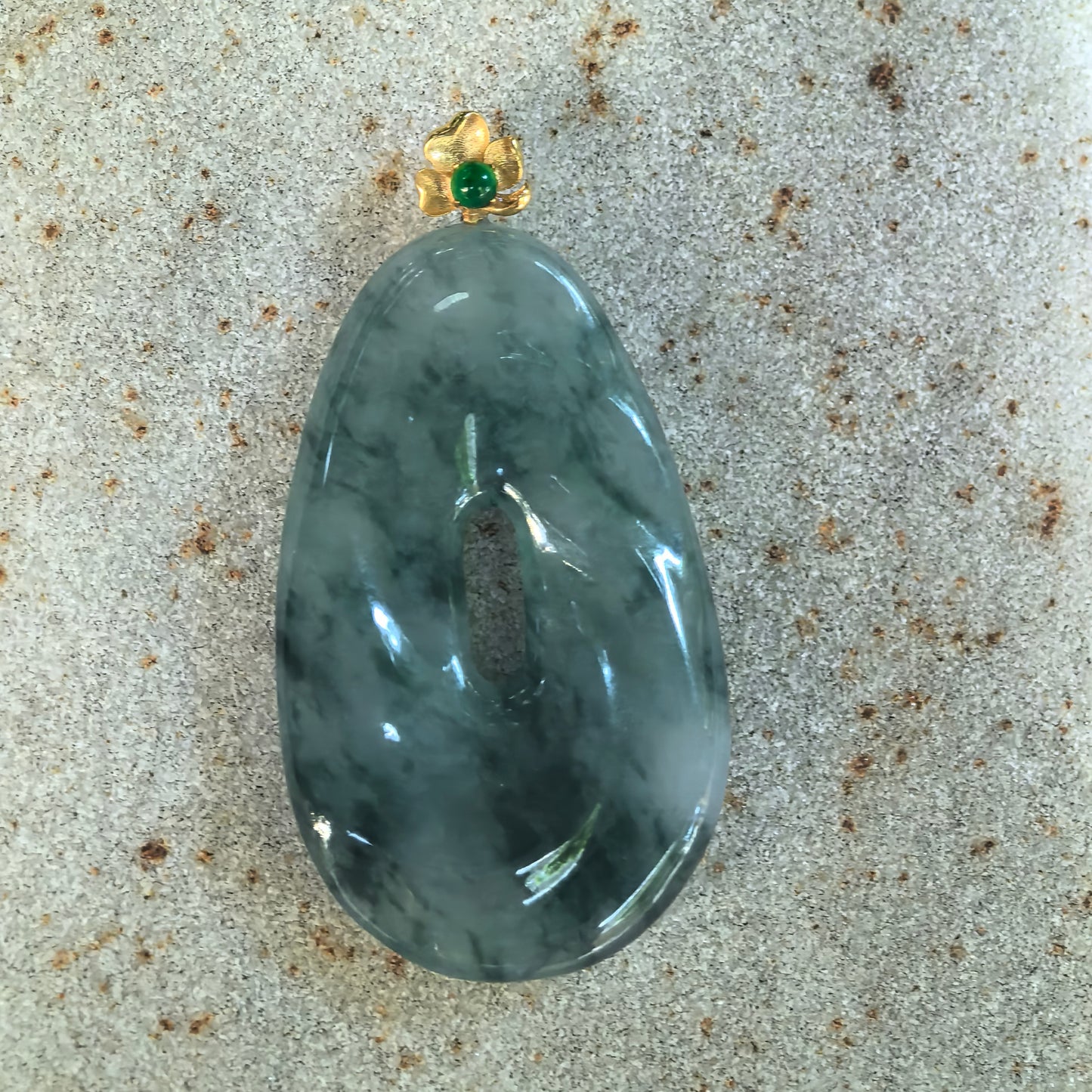 Front detail of NGTC certified dark ink green icy glutinous jadeite pendant showing the distinctive spiral-inspired design and natural mottled texture.