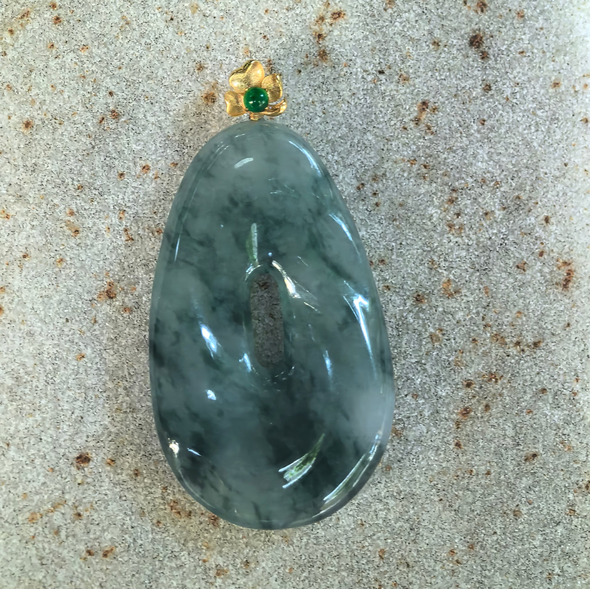 Front detail of NGTC certified dark ink green icy glutinous jadeite pendant showing the distinctive spiral-inspired design and natural mottled texture.