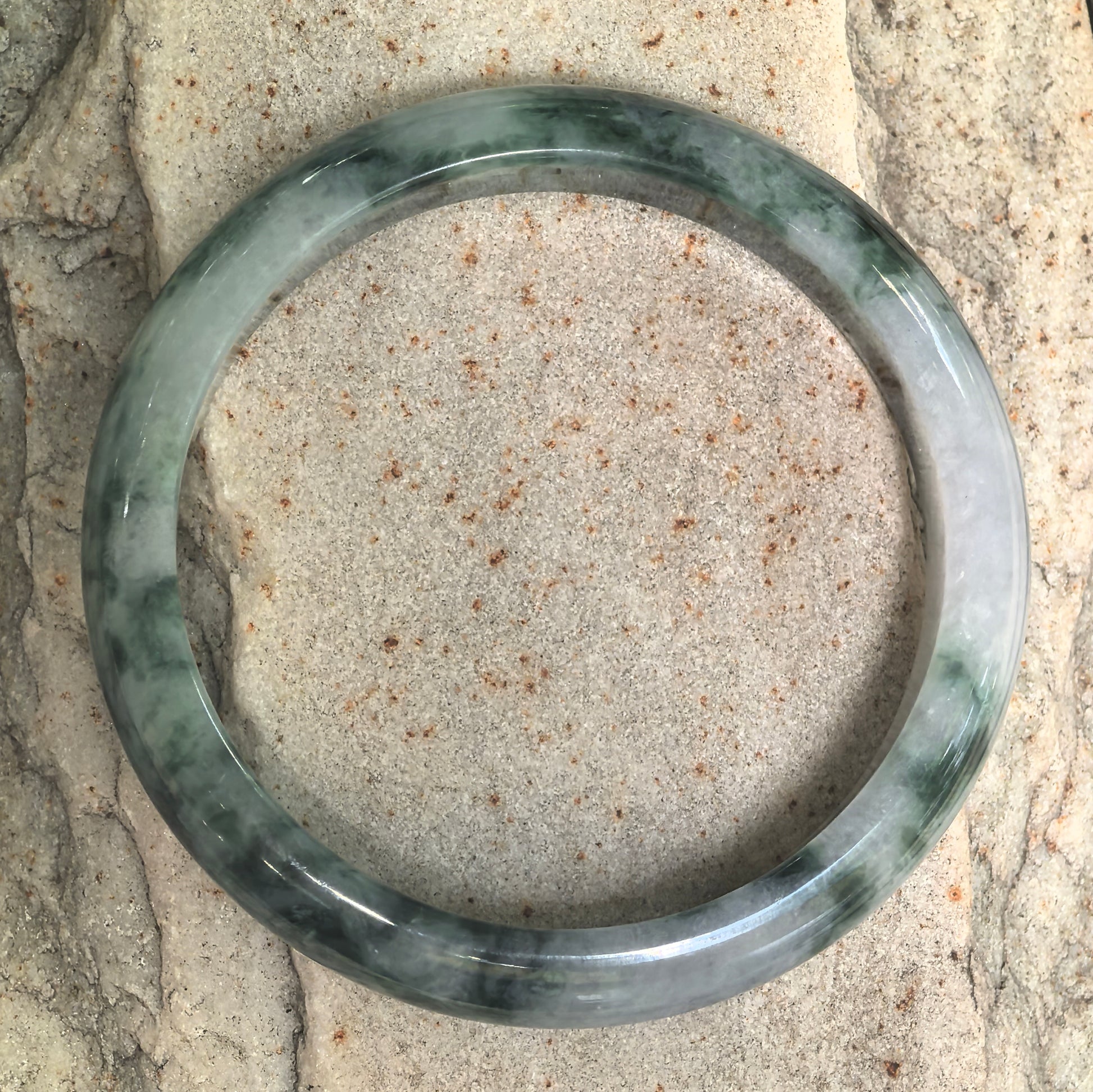Top view of Burmese jadeite bangle showing the contrast between deep ink-green floating patterns and the lighter green base.