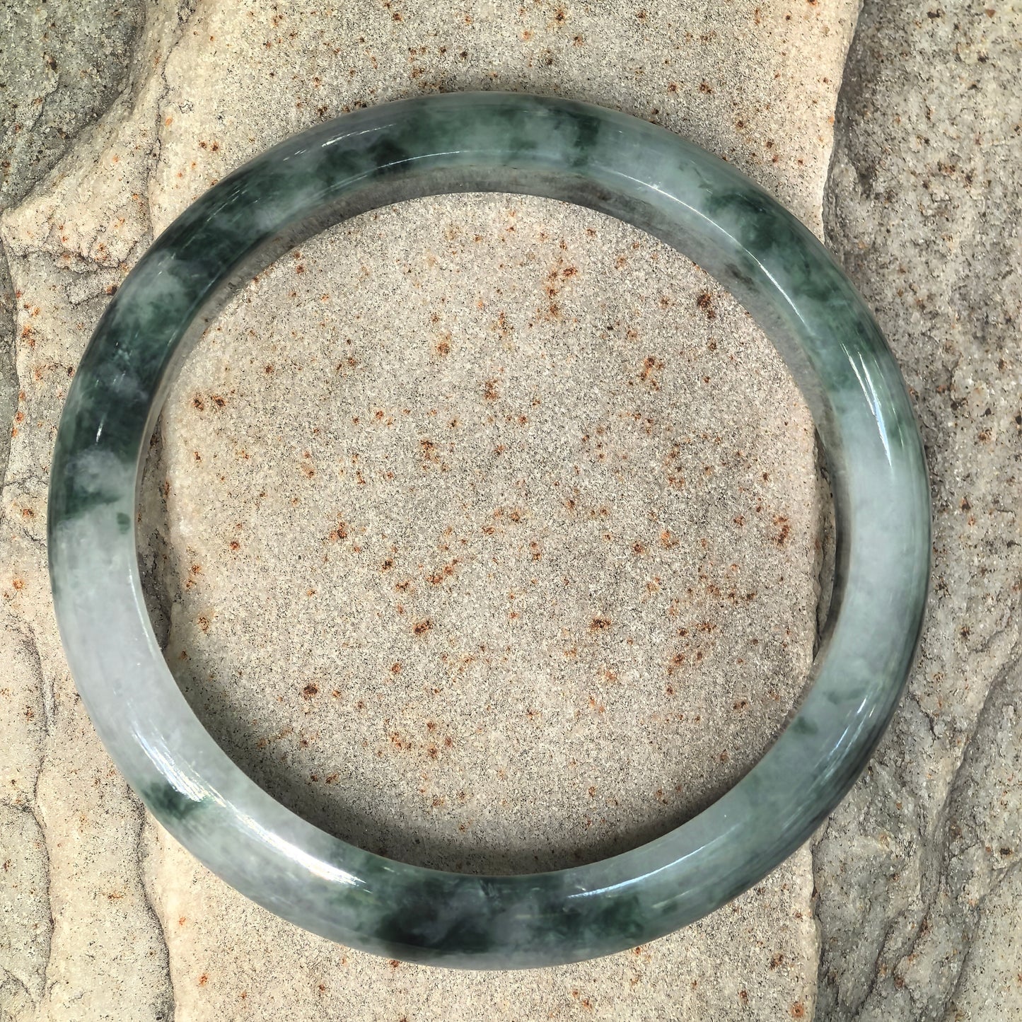 Full product view of glutinous dark green floating flower jadeite D-shape bangle showing its circular form and natural color variation.