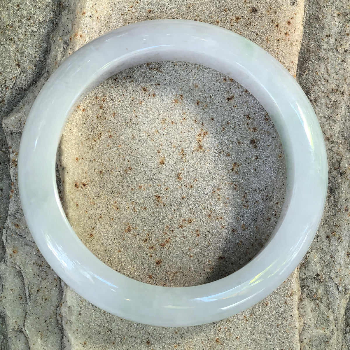 Top view of white and light green glutinous jadeite D-shape bangle showing its polished surface and natural color distribution.