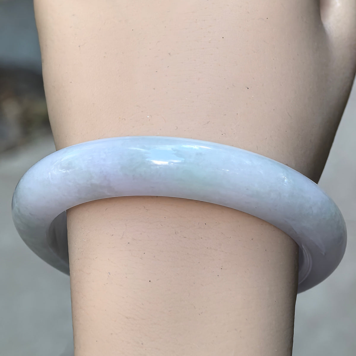 Front wrist view of pale lavender and light green glutinous jadeite D-shape bangle showing soft translucency and polished luster.