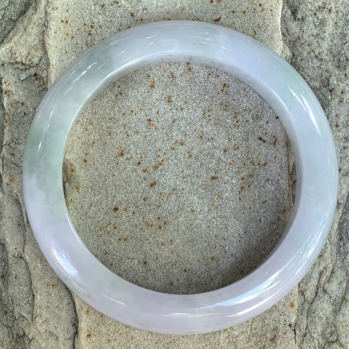 Top view of pale lavender and light green glutinous jadeite D-shape bangle showing natural color variation and visible lines.