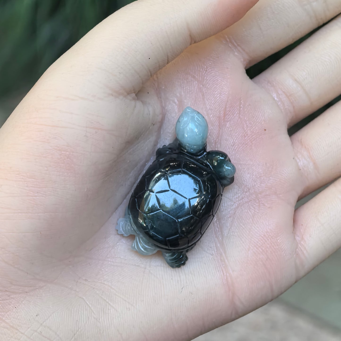 Hand-held view of deep green and light green Burmese jadeite turtle ornament showing the three-dimensional shell carving.