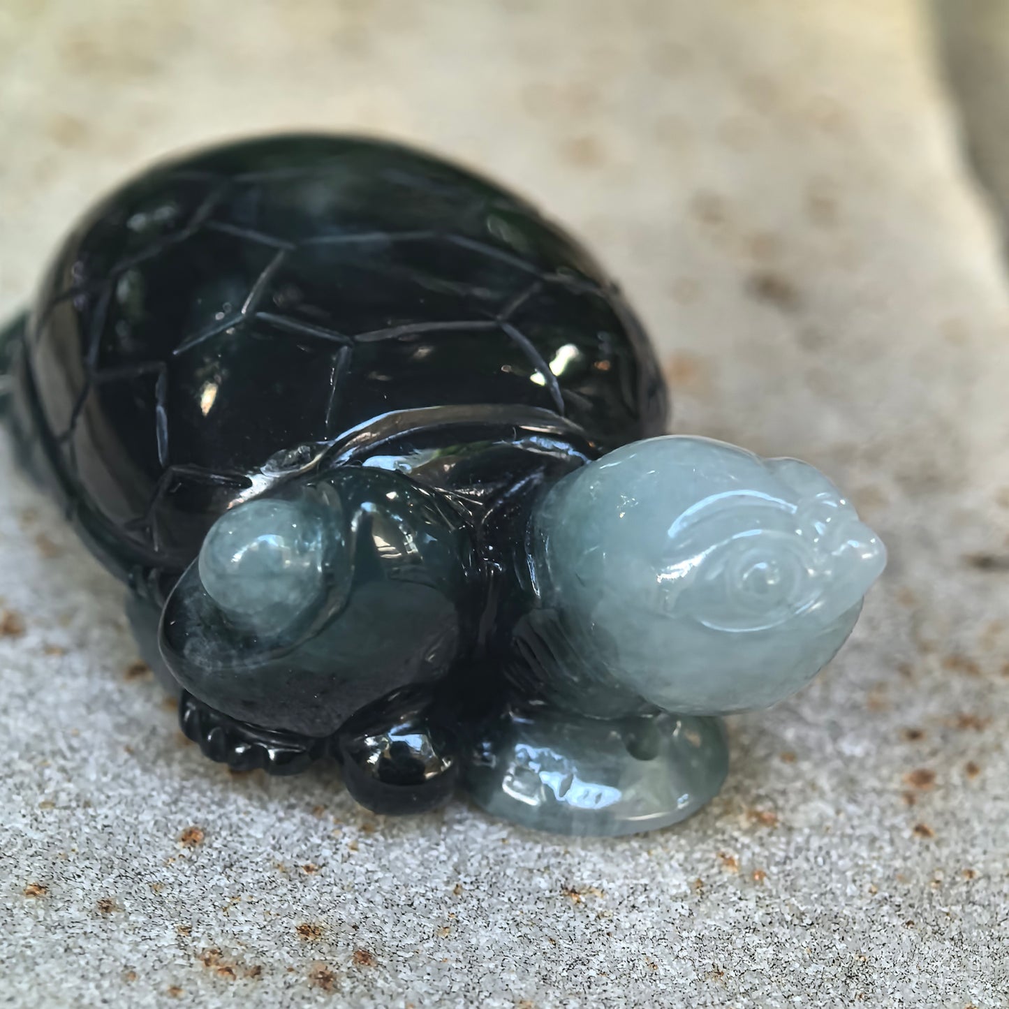 Close-up of the jadeite turtle ornament showing the light green carved head, deep green body, glossy luster, and detailed three-dimensional craftsmanship.