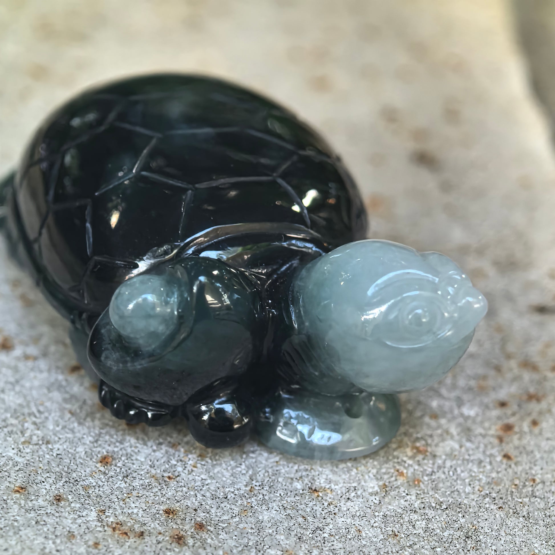 Close-up of the jadeite turtle ornament showing the light green carved head, deep green body, glossy luster, and detailed three-dimensional craftsmanship.
