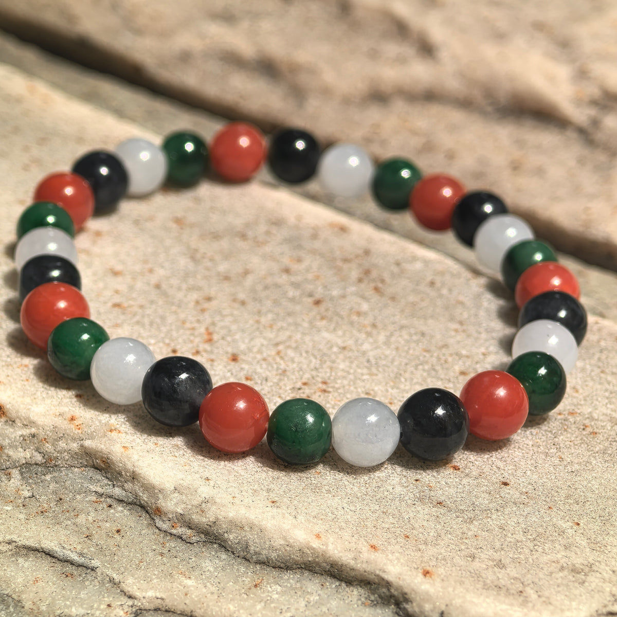 Palestine-inspired multicolor bracelet displayed on stone with polished jadeite beads and red Nanhong agate accents.