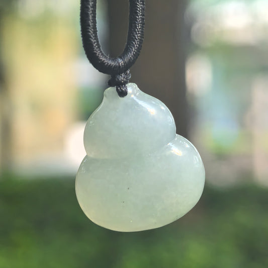 Close-up of a light green glutinous jadeite gourd pendant suspended from a black cord, showing soft translucency and curved contours.