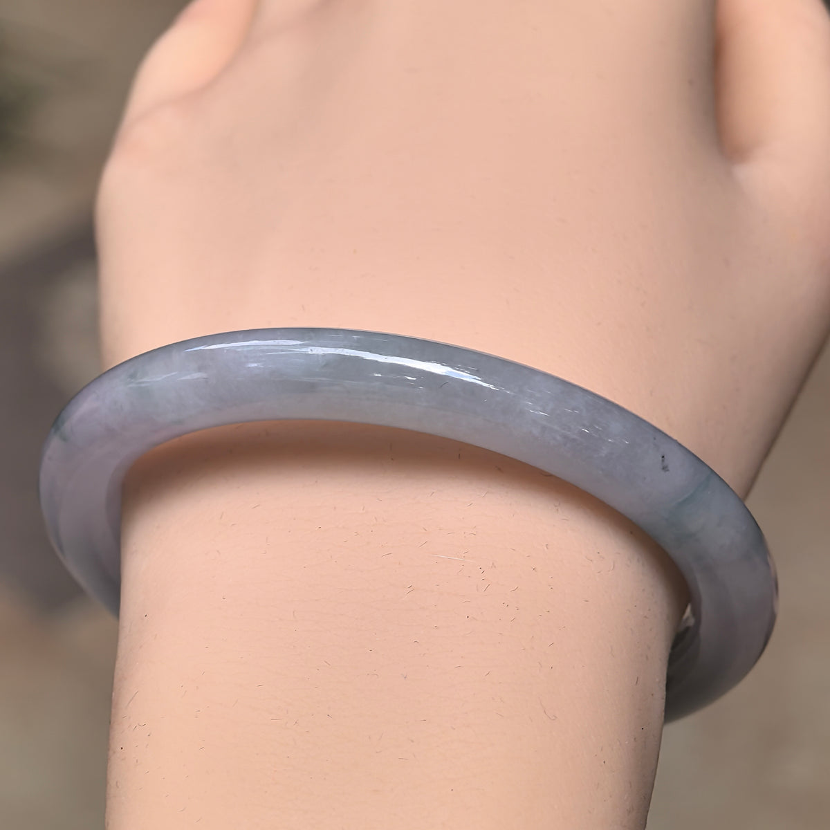 Front wrist view of a pale lavender round-bar jadeite bangle showing its slender rounded band and polished luster.