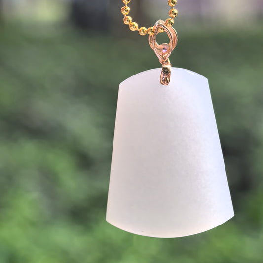 White Hetian jade tapered plain plaque pendant hanging from a display chain, showing its curved lower edge and decorative 18K gold bail.