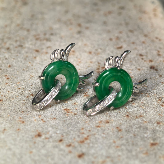 Angled view of green jadeite little devil earrings on stone, with polished jadeite discs and sculpted 18K gold details.
