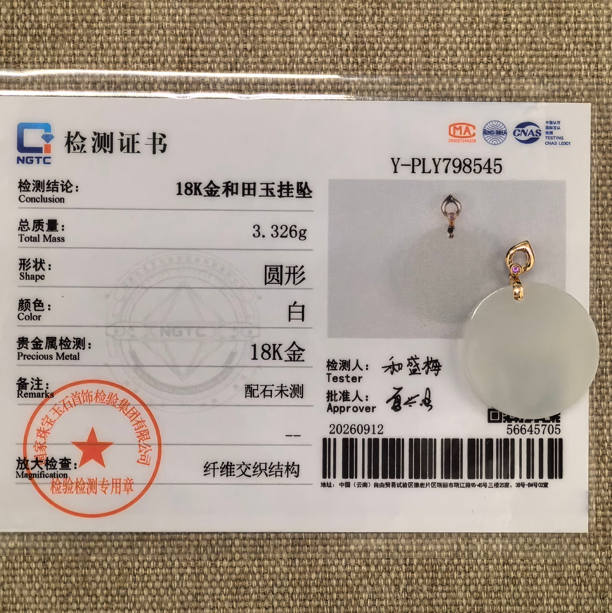 White Hetian jade round plain plaque pendant displayed with its matching NGTC certificate on a woven background.