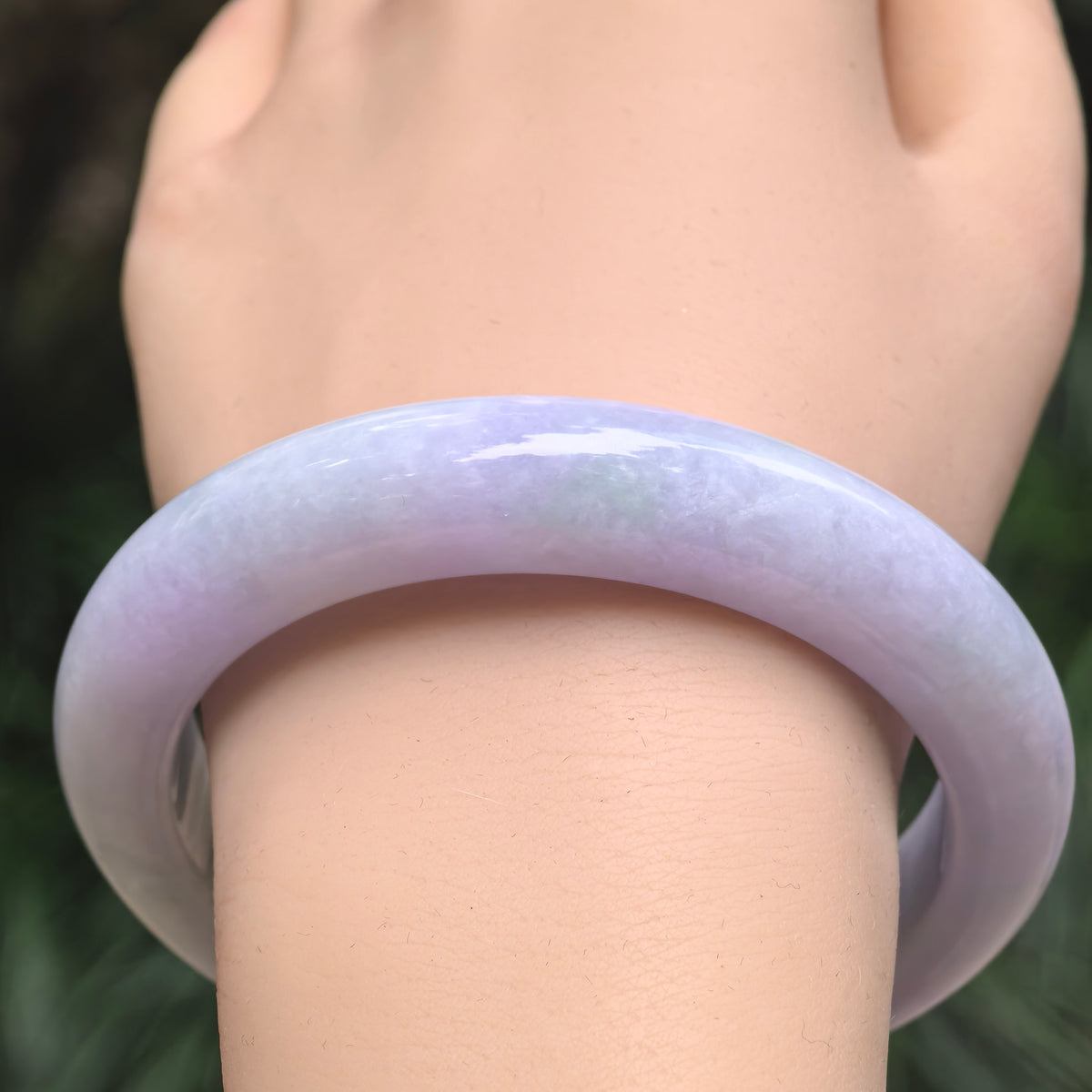 Front wrist view of a pale lavender glutinous jadeite D-shape bangle, showing its substantial band and polished rounded exterior.