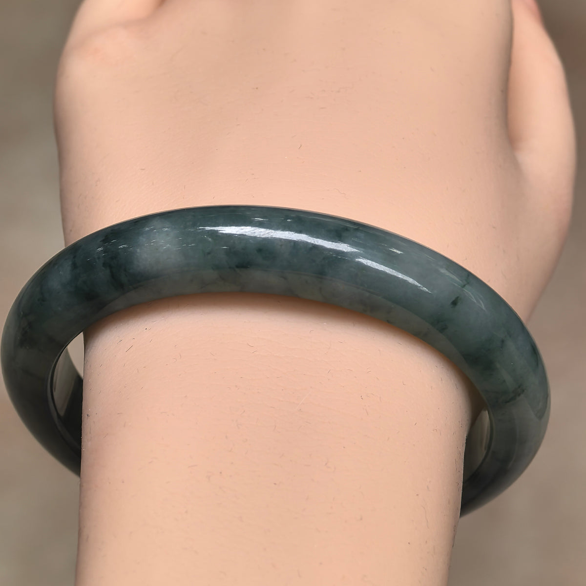 Front wrist view showing the flowing dark green markings and rounded outer face of a glutinous jadeite bangle.