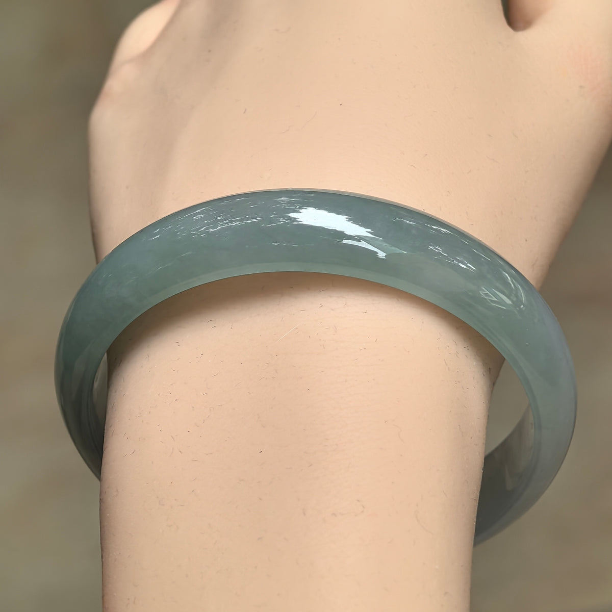 Front wrist view of a pale green D-shape jadeite bangle with soft translucency and subtle variations in tone.