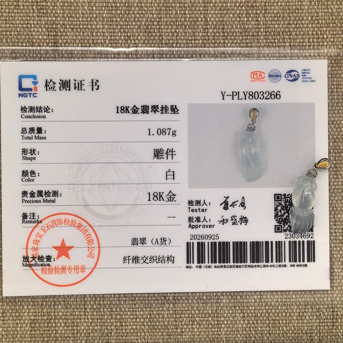 White jadeite goldfish pendant displayed with its matching NGTC certificate identifying Grade-A jadeite and 18K gold.