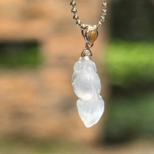 Icy white jadeite goldfish pendant suspended from a chain, showing its translucent body and 18K gold bail.