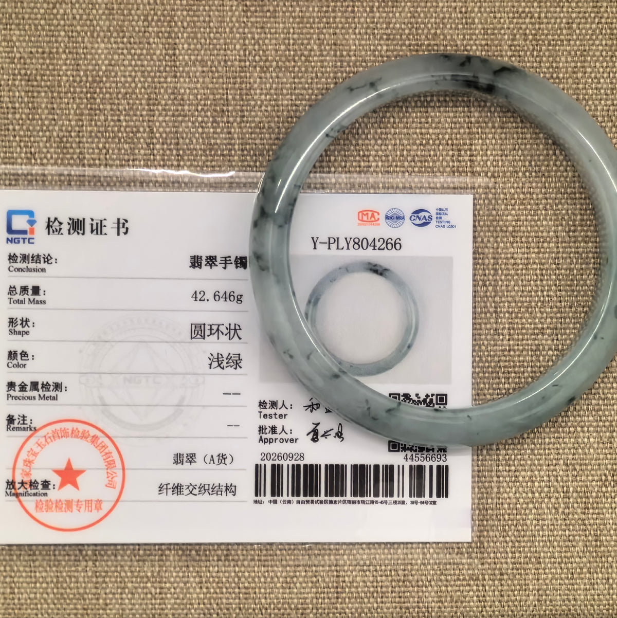 Deep green floating pattern jadeite D-shape bangle displayed over its matching NGTC Grade-A jadeite certificate.