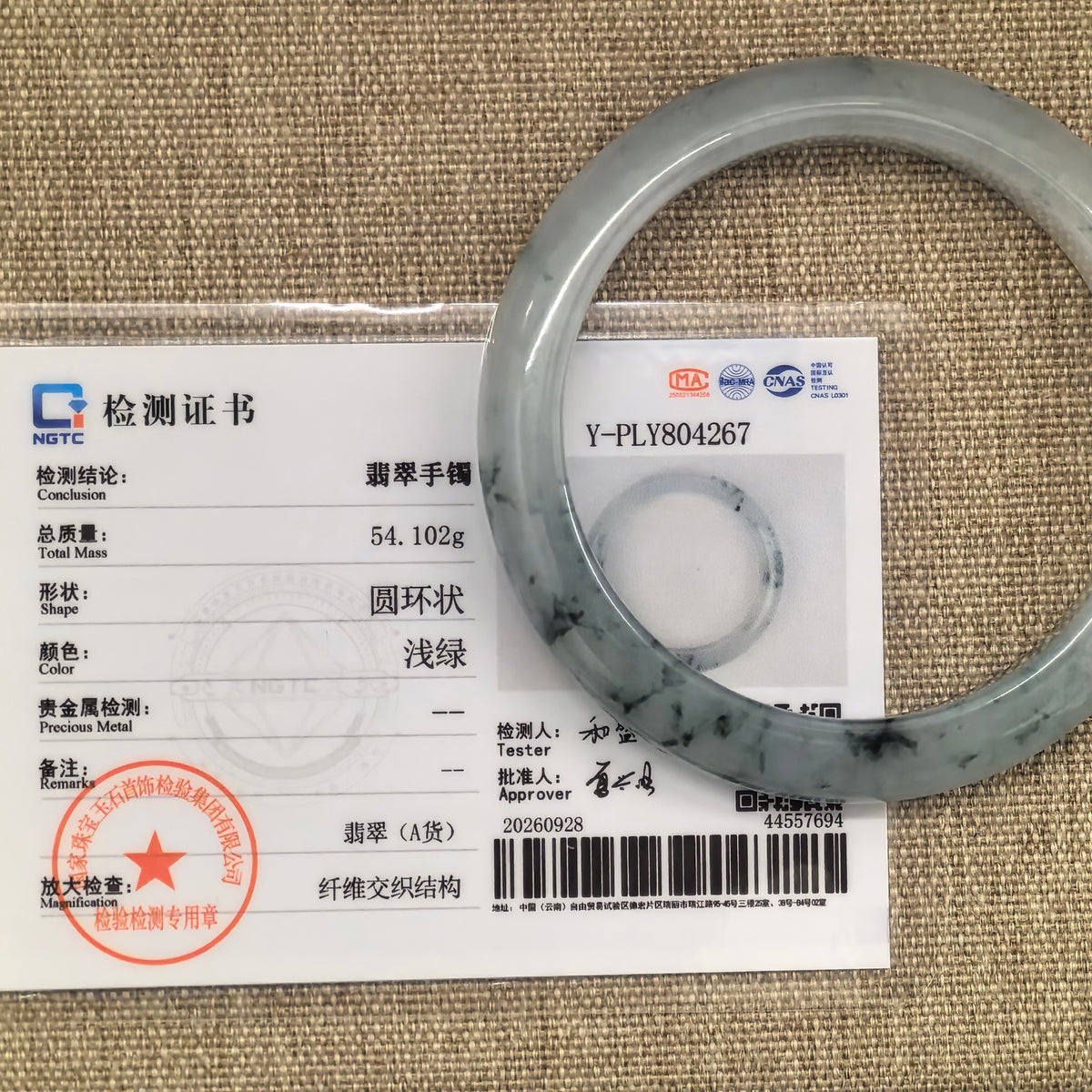 Pale green jadeite D-shape bangle with deep green floating patterns displayed over its matching NGTC Grade-A jadeite certificate.