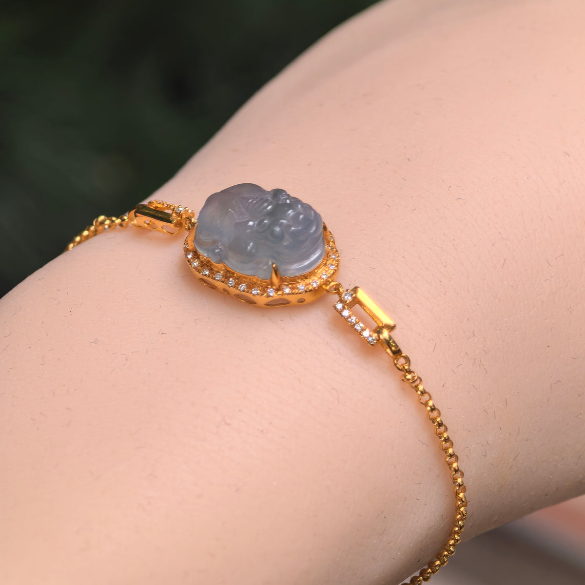 Grayish purple jadeite Pixiu bracelet worn on a wrist, showing the raised carving, 18K gold diamond halo and delicate chain.
