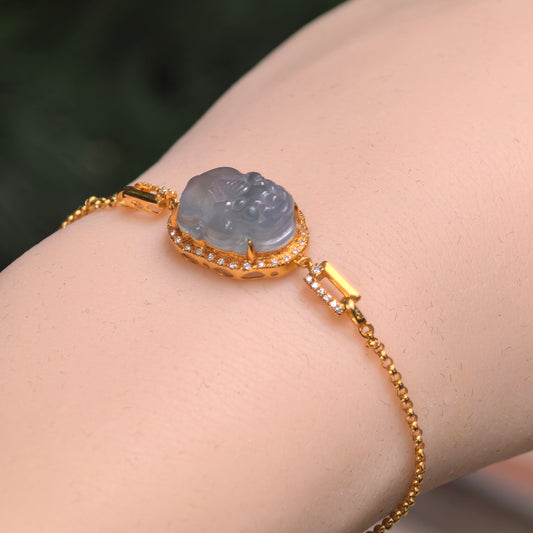 Grayish purple jadeite Pixiu bracelet worn on a wrist, showing the raised carving, 18K gold diamond halo and delicate chain.
