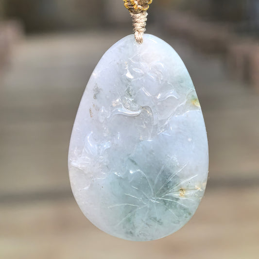 Blue glutinous jadeite Floral Plaque Pendant hanging from a knotted cord, showing flower and leaf relief carving with deeper color accents near the bottom.