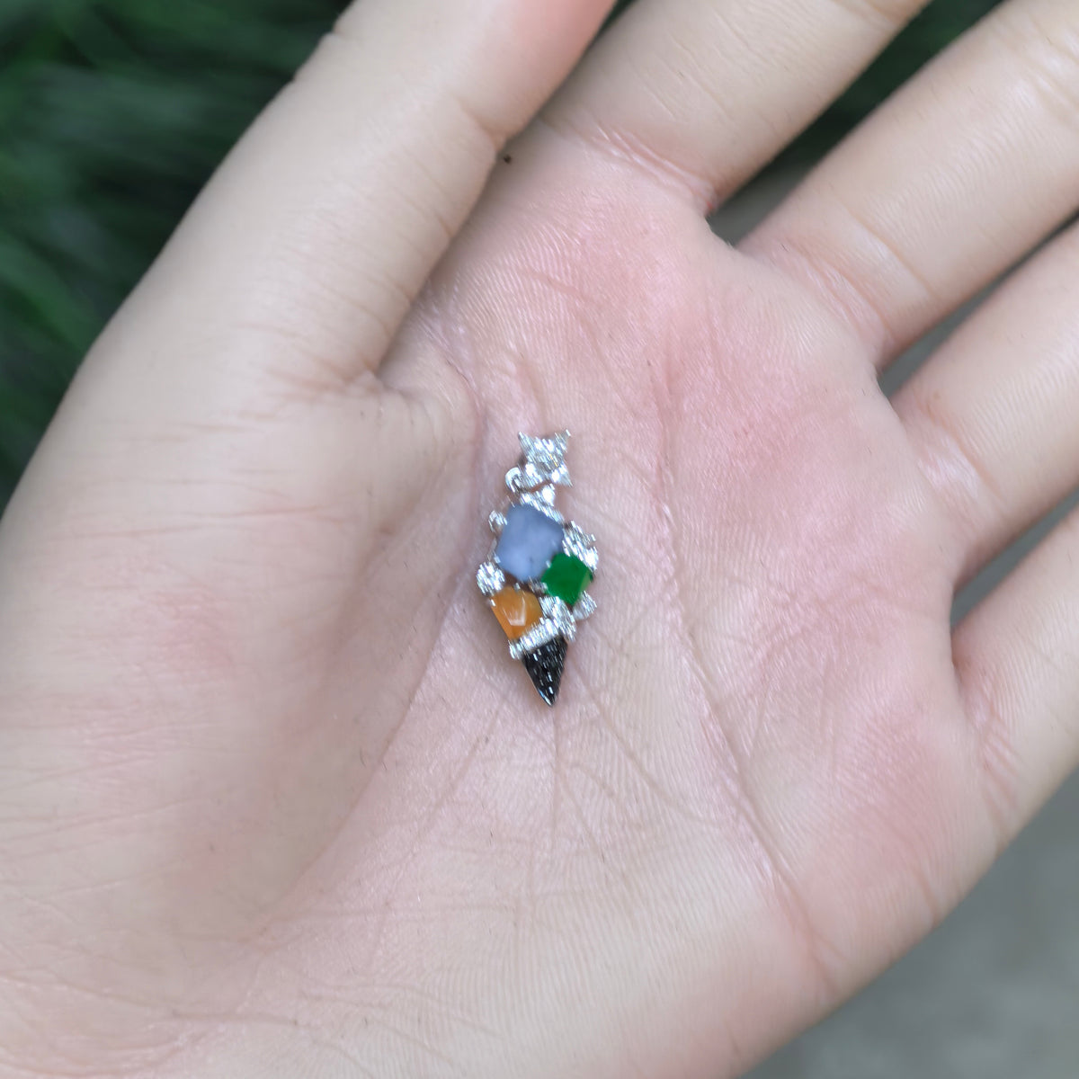 Icy multicolor jadeite ice cream cone pendant resting in a palm, showing its overall silhouette and decorative bail.