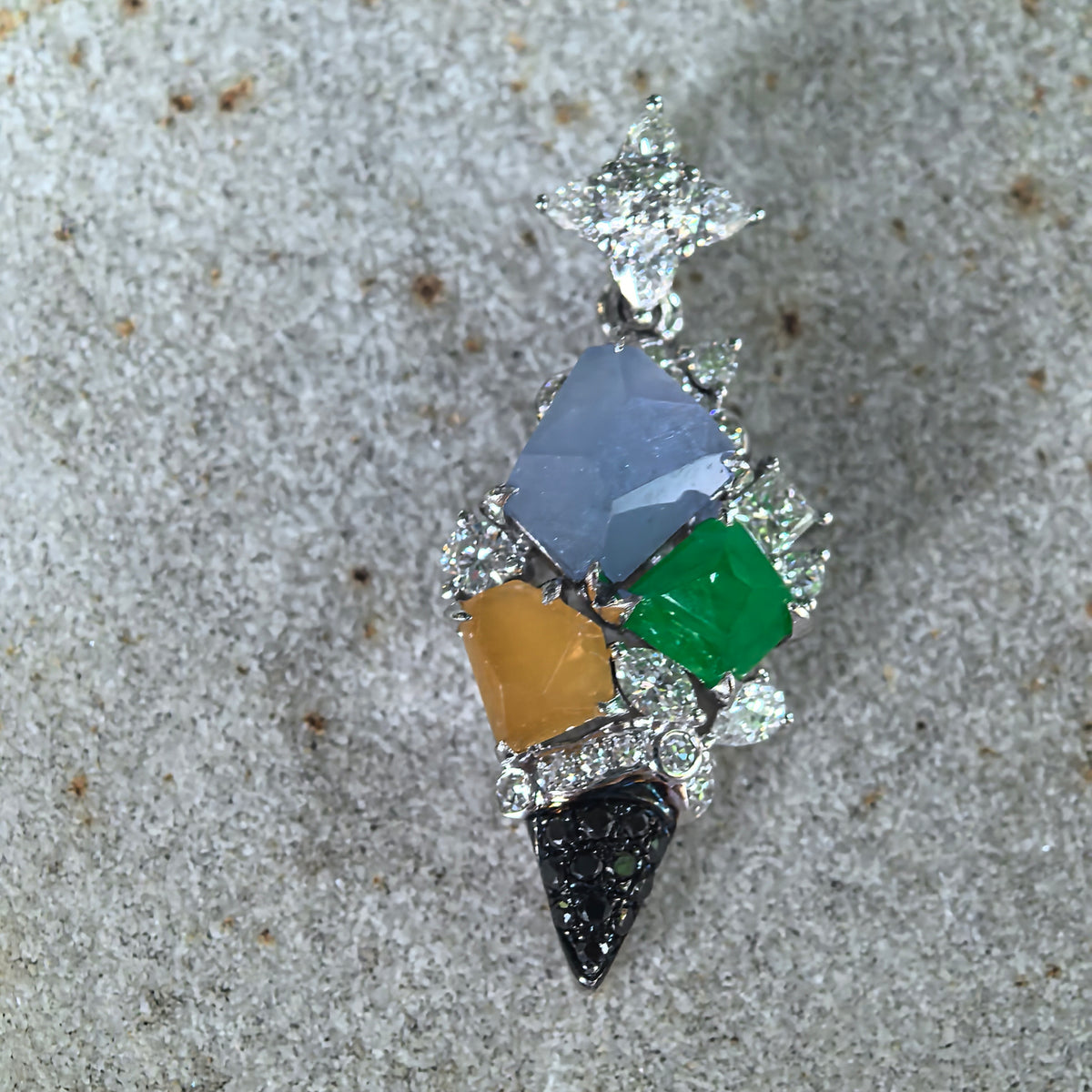 Front view of a multicolor jadeite ice cream cone pendant on stone, showing freeform jadeite pieces, diamond accents and black stones on the cone.