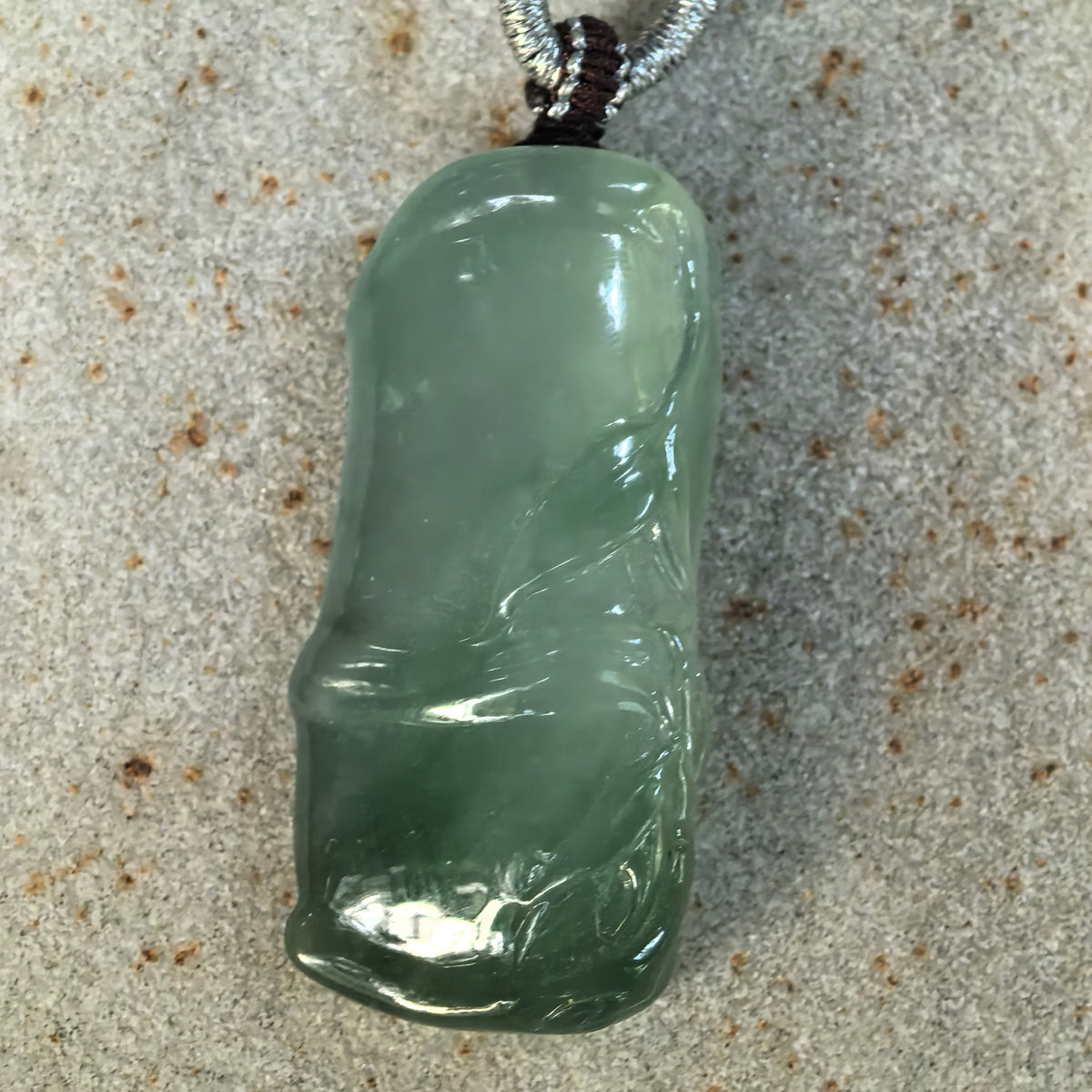 Front view of the green jadeite Bamboo Pendant on stone, highlighting its elongated shape and detailed bamboo leaf carving.