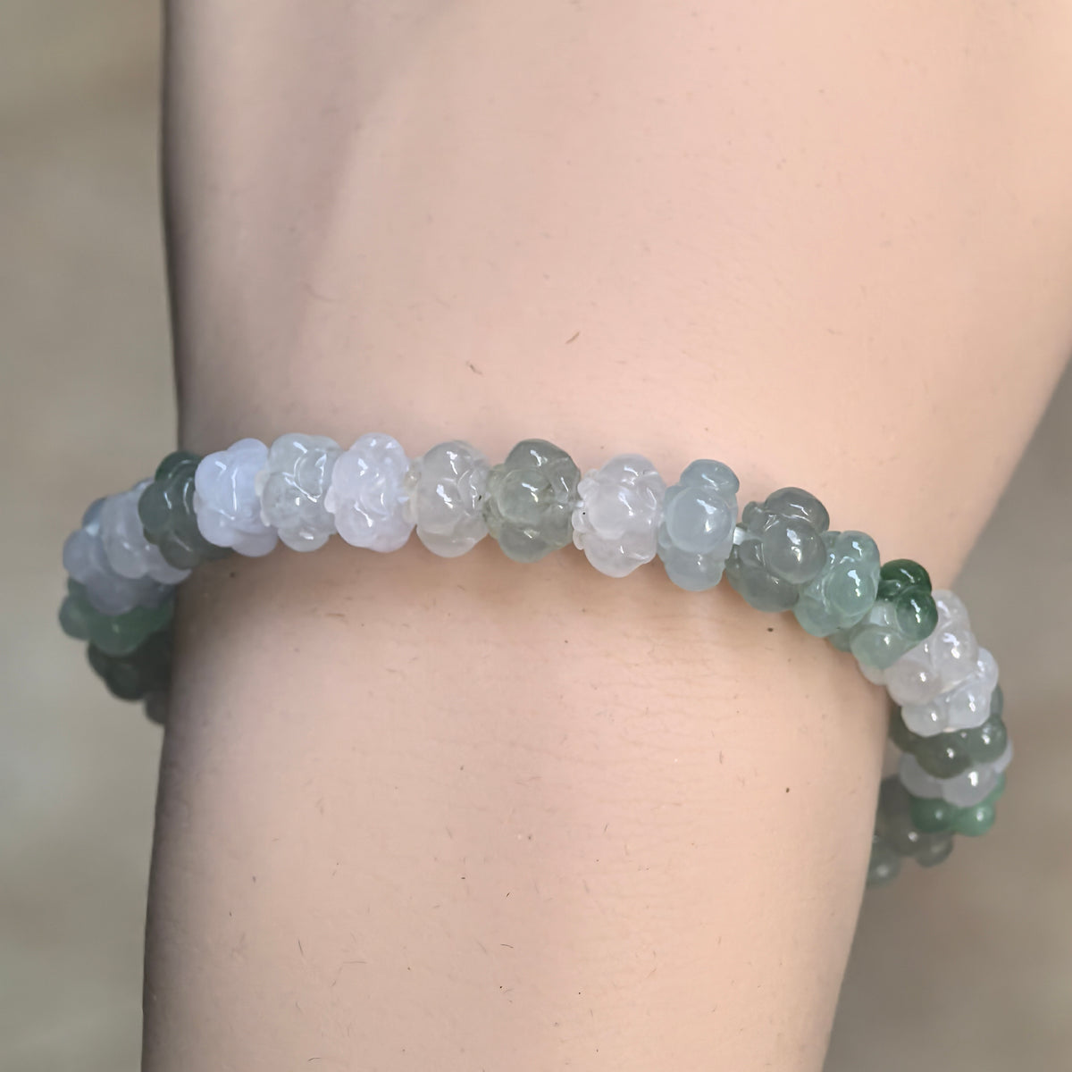 Front wrist view of a jadeite lotus bead bracelet with white and light green beads interspersed with deeper green accents.