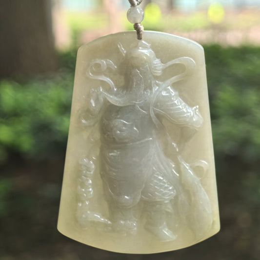 Glutinous gray-green Guan Gong jadeite plaque pendant hanging from a cord, showing the commanding figure and gently curved outline.