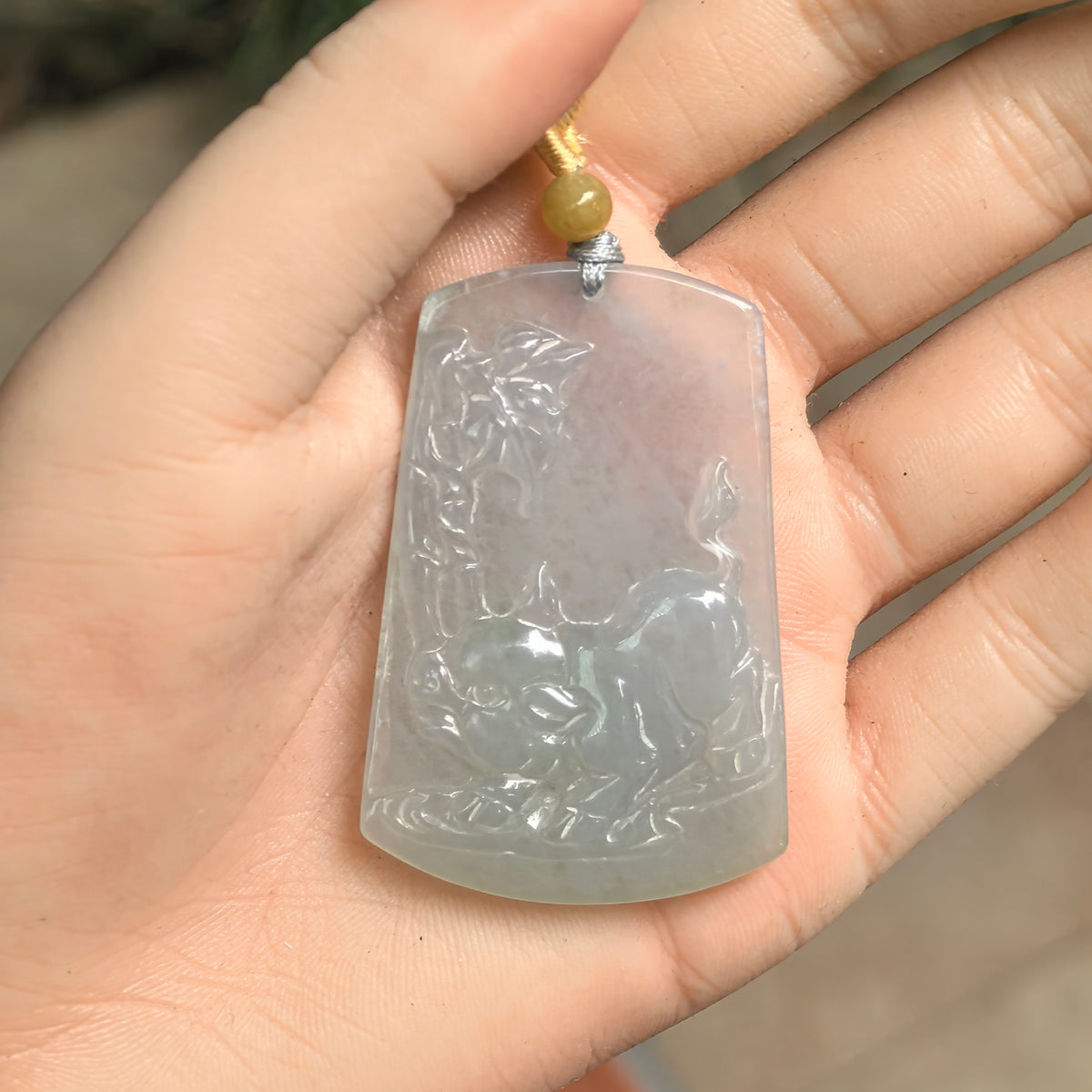 Icy glutinous pale green jadeite Pig Plaque Pendant resting in a palm, showing the pig relief, leafy details and gently curved edges.