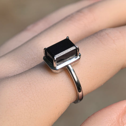 Black rectangular jadeite ring worn on a finger, showing its polished face, beveled edges and Pt950 platinum setting.