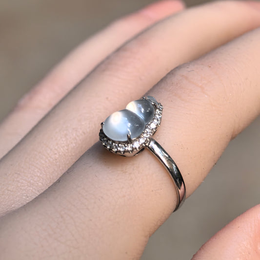 White gourd jadeite ring worn on a finger, showing its luminous rounded stone, clear accent halo and slim 18K gold band.