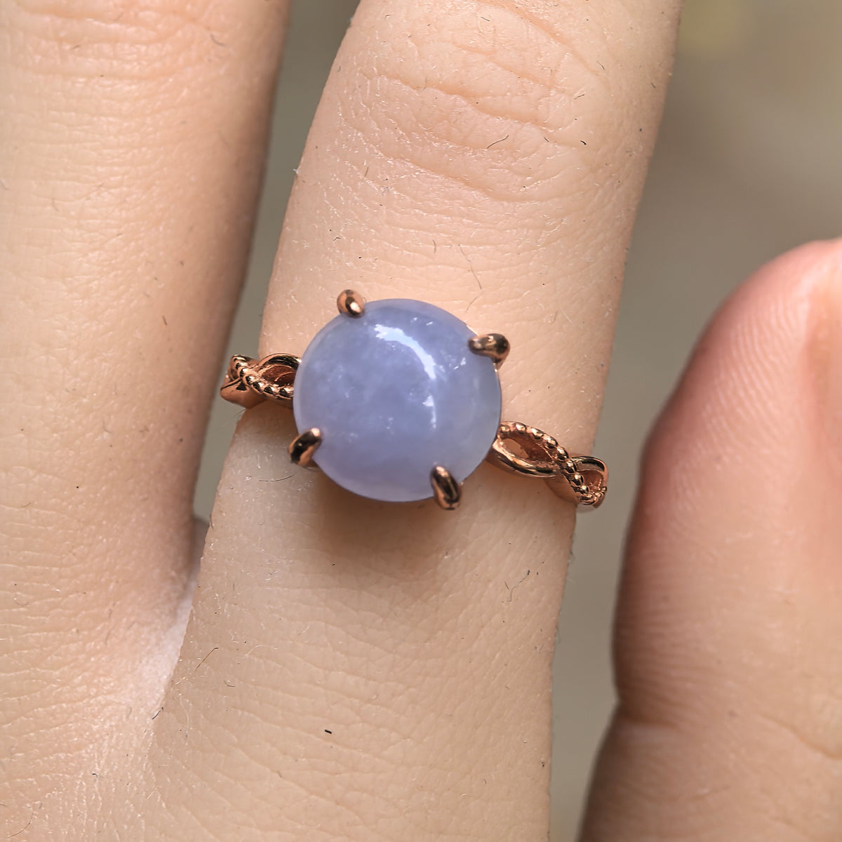 Front close-up of a purple jadeite ring worn on a finger, with four prongs and twisted S925 silver shoulders in a warm gold tone.