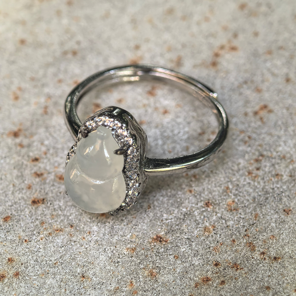 Angled view of the white jadeite gourd ring on a finger, highlighting the rounded carving, raised S925 silver setting and clear accent halo.