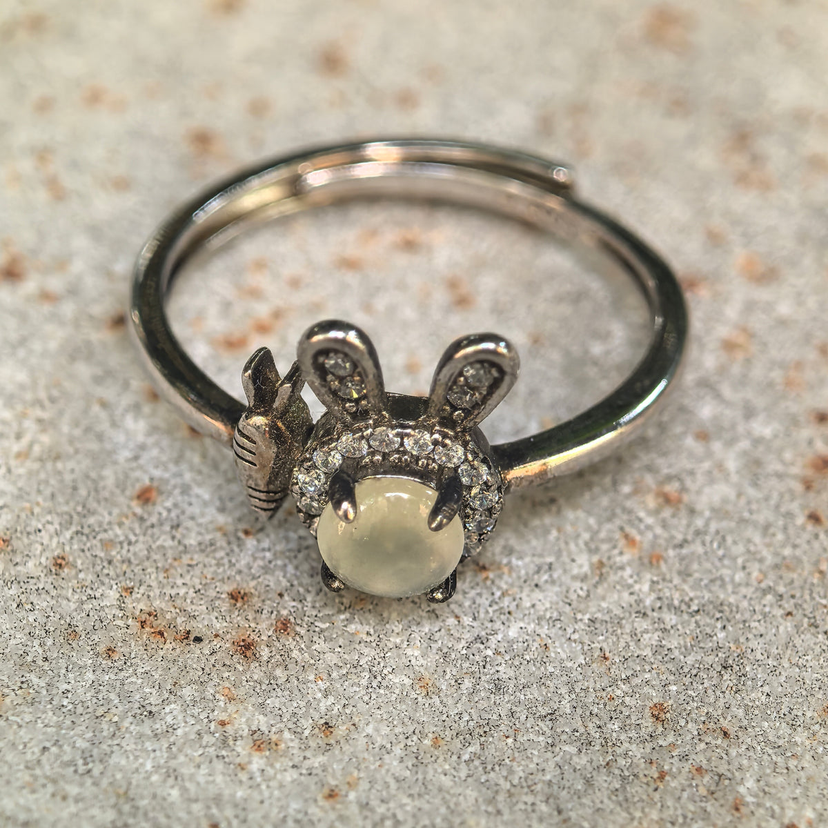 Close-up of the white jadeite rabbit ring on stone, highlighting the clear accent halo, upright silver ears and carrot motif.