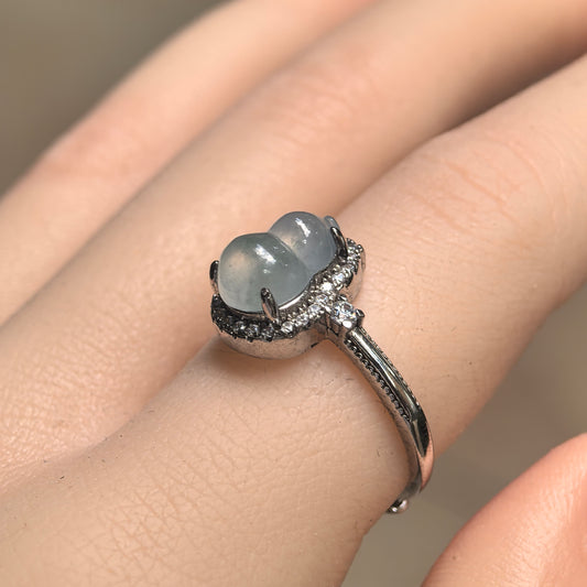 Angled view of a pale green jadeite gourd ring on a finger, showing the rounded carving, raised prong setting and clear accent stones in S925 silver.