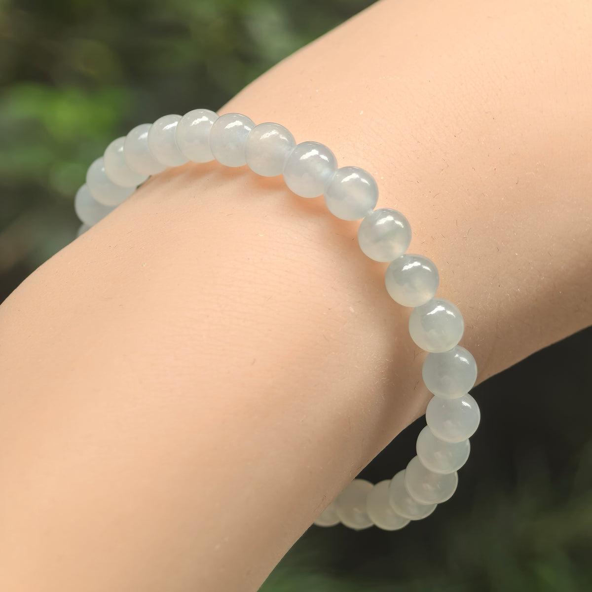 Angled wrist view of an icy white jadeite bracelet with polished round beads and soft translucency.