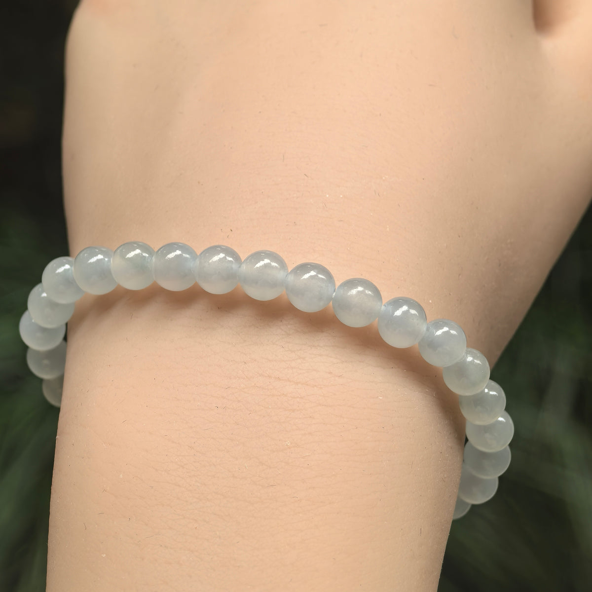Front wrist view of a white jadeite bead bracelet arranged in a slender single strand.