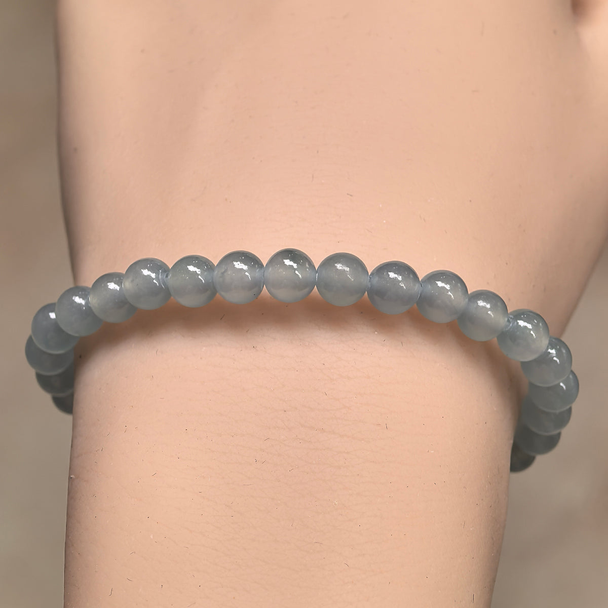 Front wrist view of a light blue jadeite bead bracelet showing soft translucency and subtle tonal variations.