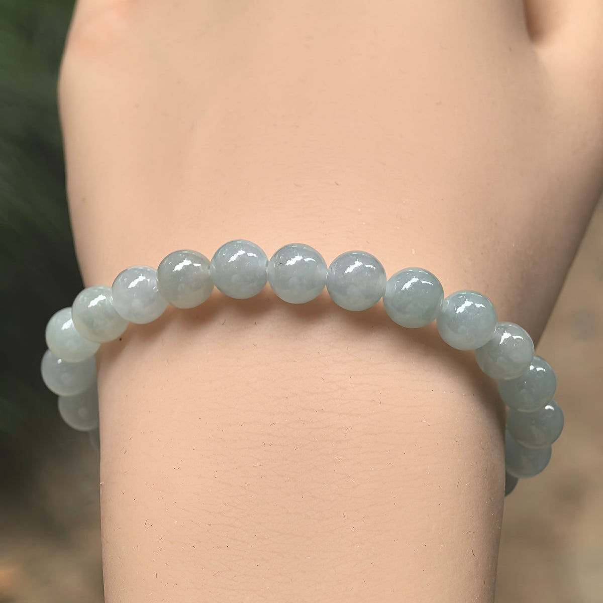 Front wrist view of an icy glutinous light green jadeite bead bracelet showing subtle variations in bead color.
