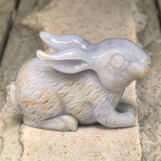 Side view of a white jadeite rabbit facing right, with natural golden-brown flecks across its textured body and face.