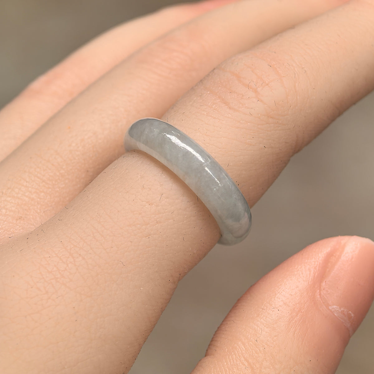 Angled view of a white jadeite ring band on a finger, showing its rounded outer profile and polished surface.