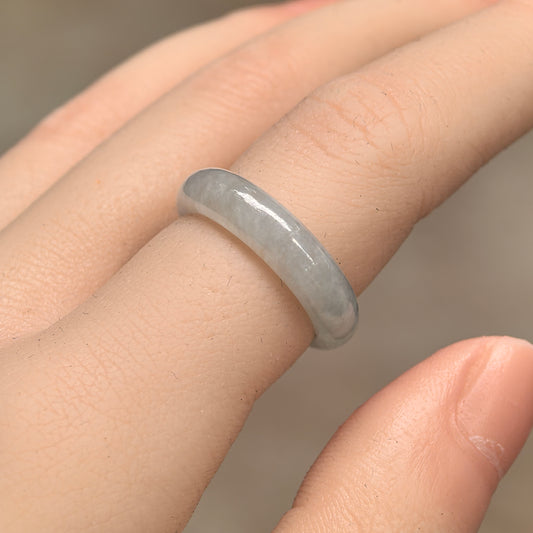 Angled view of a white jadeite ring band on a finger, showing its rounded outer profile and polished surface.