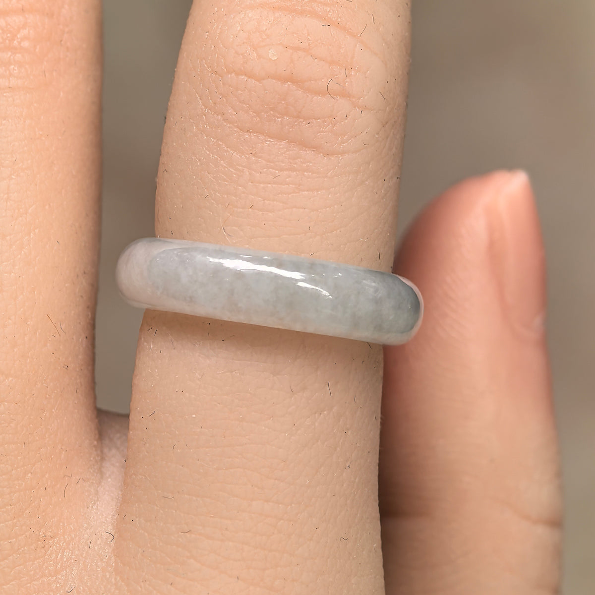 Front view of a white glutinous jadeite ring band worn on a finger, showing its slim band and softly clouded texture.
